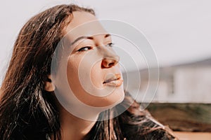 Happy young smiling woman with freckles outdoors portrait. Soft sunny colors. Outdoor close-up portrait of a young