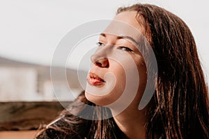 Happy young smiling woman with freckles outdoors portrait. Soft sunny colors. Outdoor close-up portrait of a young