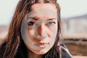 Happy young smiling woman with freckles outdoors portrait. Soft sunny colors. Outdoor close-up portrait of a young