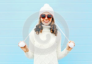 Happy young smiling woman wearing a heart shape sunglasses, knitted hat, sweater over blue