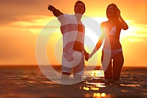 Happy young  spending time together on sea beach at sunset