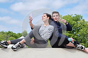 Happy young sport couple taking a selfie while sitting at a park