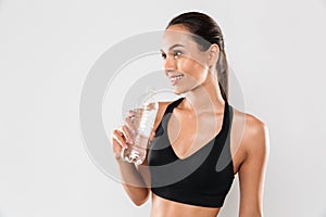 Happy young sports woman posing isolated drinking water.