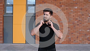 A happy young sportsman with earphones is walking outside on the bridge in the morning.