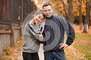 Happy sporty couple gently hugging in the autumn park.