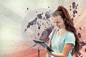 Happy young student woman holding a tablet against white, red and purple splattered background