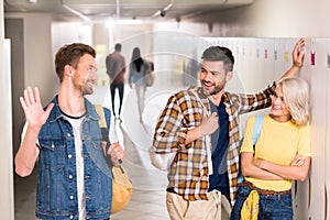 happy young students greeting each other