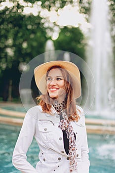 Happy young stylish woman smiling in park in hat