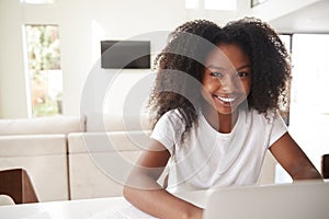 Happy young teenage African American  girl using laptop computer at home, close up