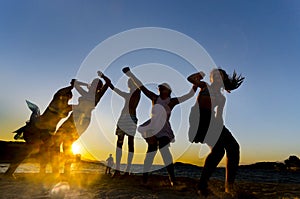 Happy young teens dancing at the beach at beautiful summer sunset photo