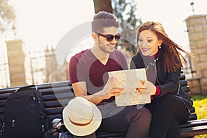 Happy young tourist couple sitting on the bench