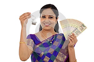 Happy young traditional woman holding Indian currency and house