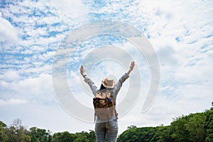 Happy young traveler woman backpacker raised arm up to sky enjoy