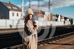 Happy young traveler woman with cup of coffee at train station platform