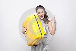 Happy young traveller in striped dress standing and holding yell