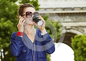 Happy young trendy woman while drinking coffee on Champ Elysees