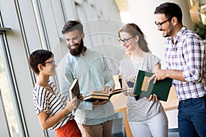 Happy young university students studying with books in library