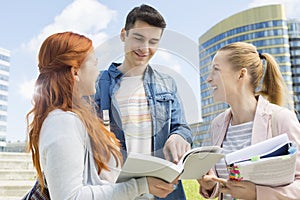 Happy young university students studying outdoors