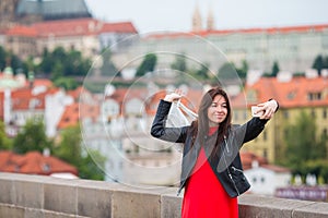 Happy young urban woman in european city on the famous bridge. Caucasian tourist walking in Prague, Czech Republic