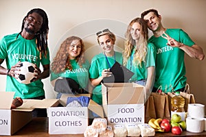 Happy young volunteers donating clothes and food for charity, indoors