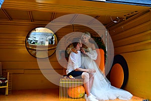 Happy young wedding couple kissing and hugging in yellow room
