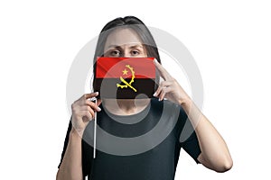 Happy young white woman holding flag Angola flag and covers her face with it isolated on a white background