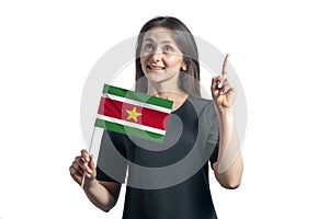 Happy young white woman holding flag of Suriname and points thumbs up isolated on a white background