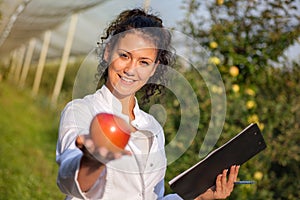 Happy young woman agronomist with red apple in her hand