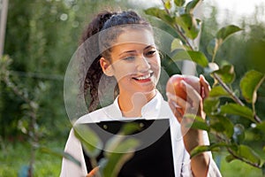 Happy young woman agronomist with red apple in her hand