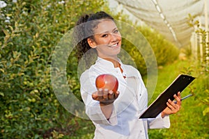 Happy young woman agronomist with red organic apple in her hand