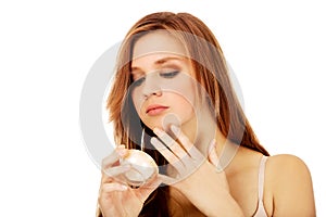 Happy young woman applying cream moisturizer