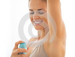 Happy young woman applying deodorant on underarm photo