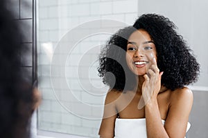 Happy young woman applying face cream