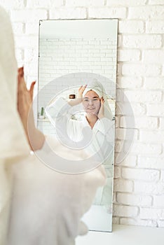 Happy young woman applying face scrub on her face