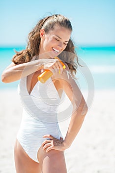 Happy young woman applying sun block creme