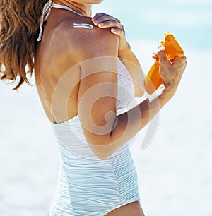 Happy young woman applying sun block creme on beach