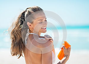 Happy young woman applying sun screen creme