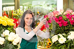 Happy young woman arranging flowers florist shop