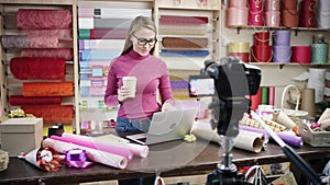 Happy young woman as florist in a flower shop designs and creates arrangements of flowers in wreaths, bouquets, vases