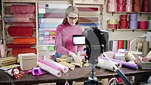 Happy young woman as florist in a flower shop designs and creates arrangements of flowers in wreaths, bouquets, vases