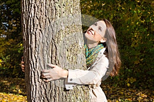 Happy young woman in autumn embrassing a tree. photo