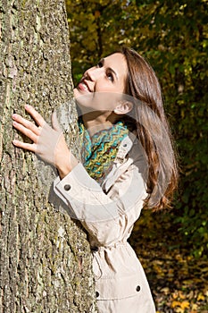 Happy young woman in autumn embrassing a tree. photo