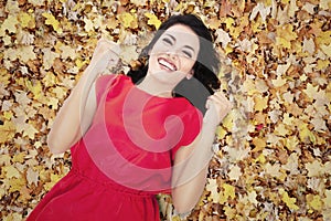 Happy young woman in autumn orange leaves