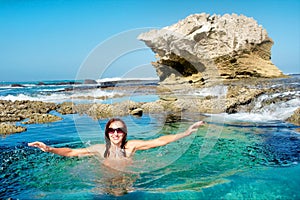 Happy young woman on awesome rocky beach