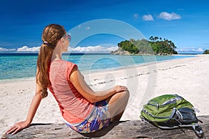 Happy young woman with backpack relaxing on coast and looking to