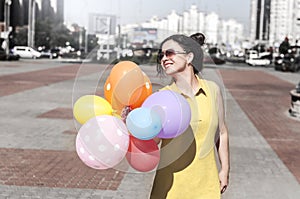 Happy young woman with balloons on the city square