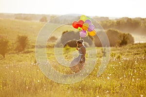 Happy young woman with balloons among a field