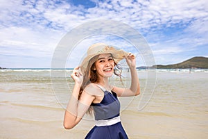 Happy young woman barefoot ware hat and walking on summer along wave of sea water and sand on the beach