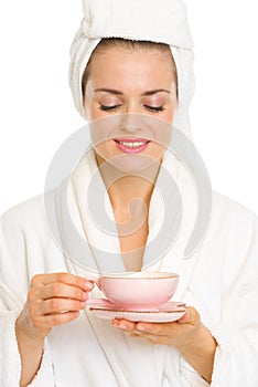 Happy young woman in bathrobe enjoying cup of tea