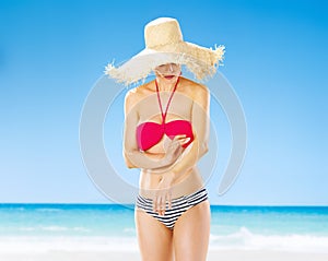 Happy young woman on beach applying sun block